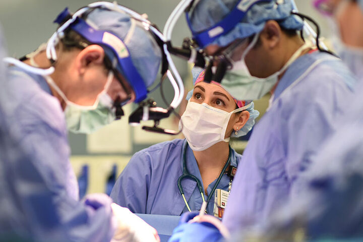 A female anesthesiologist works alongside two surgeons in an operating room.